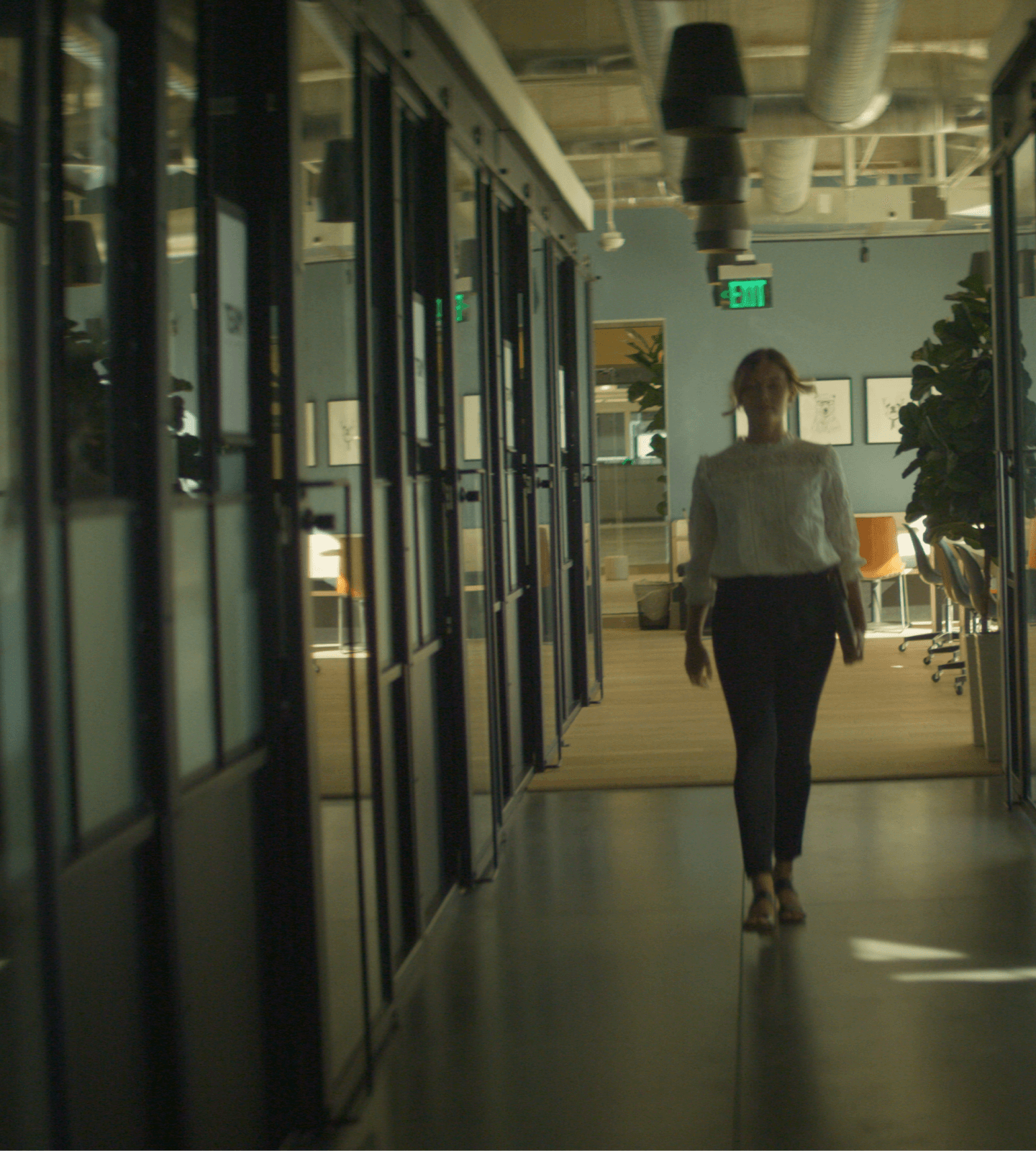 Image of woman walking down a hallway carrying a laptop.
