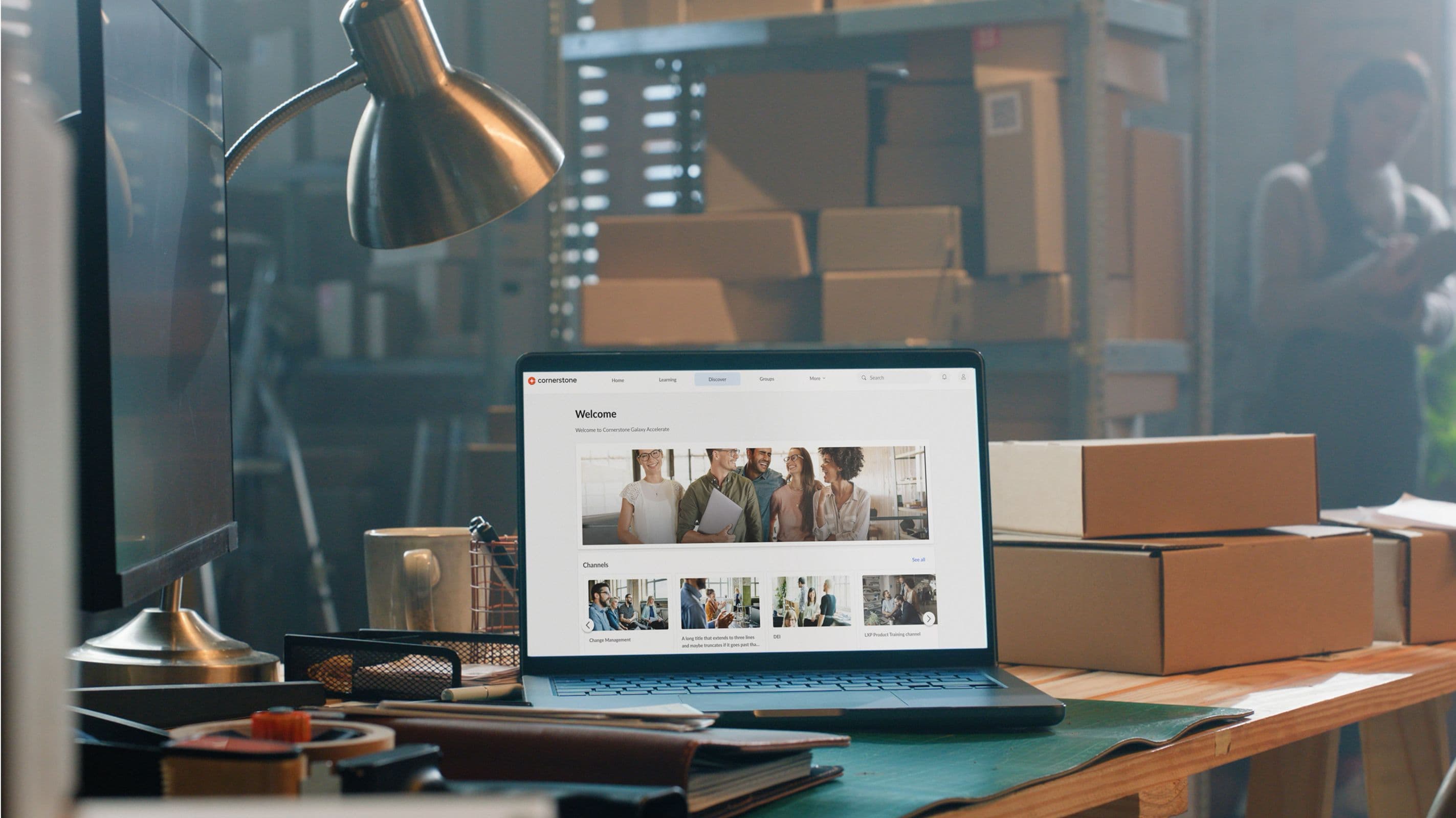 Image of a laptop, displaying Cornerstone content, sitting on a table in a warehouse surrounded by packages.