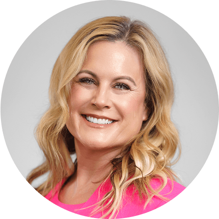 une femme en chemise rose sourit face à l'appareil photo